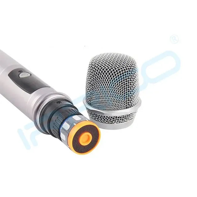 Close-up view of a handheld wireless microphone showing the internal circuit board and a detached silver mesh grille head.