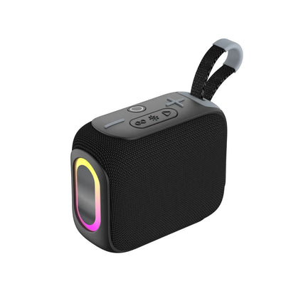 A black rectangular portable speaker with a textured fabric body, a colorful glowing RGB light ring around the front speaker grill, control buttons on the top panel, and a black fabric carrying strap with light gray accents.