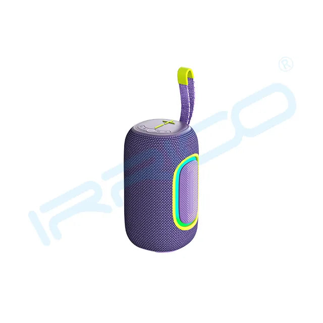 A purple cylindrical portable speaker with a textured fabric body, a glowing green and pink oval light accent on the side, a top control panel, and a purple fabric carrying strap with a yellow accent