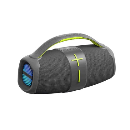 A portable cylindrical Bluetooth speaker in dark gray with a bright green carrying handle, featuring a fabric mesh body, central control band with plus and minus symbols, and a visible front speaker grill