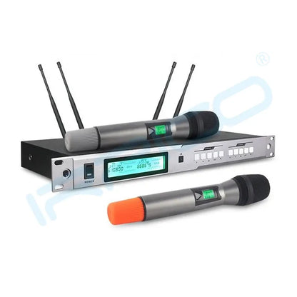 A professional UHF wireless microphone system featuring a rack-mountable receiver with a blue LCD screen and four antennas, accompanied by two handheld microphones with digital displays, one resting on the receiver and the other placed in front with an orange base.